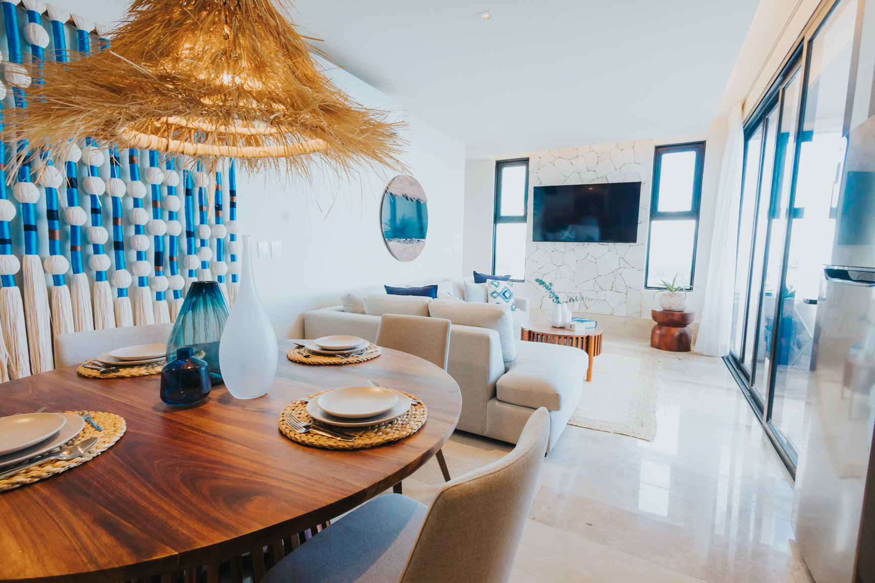 Coastal interior dining and living space with woven pendant and ocean light