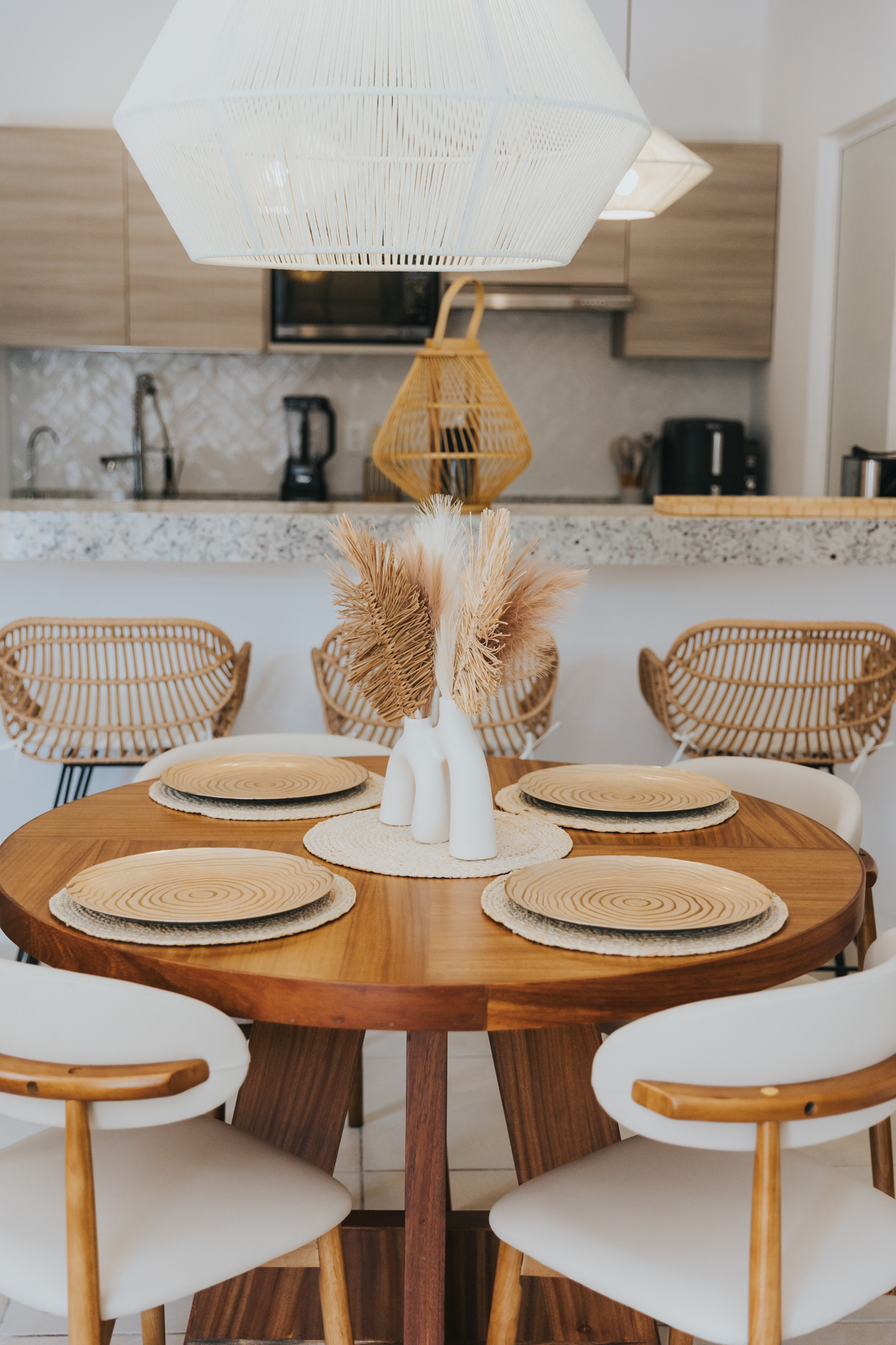 Round dining table with rattan chairs and woven pendant lights