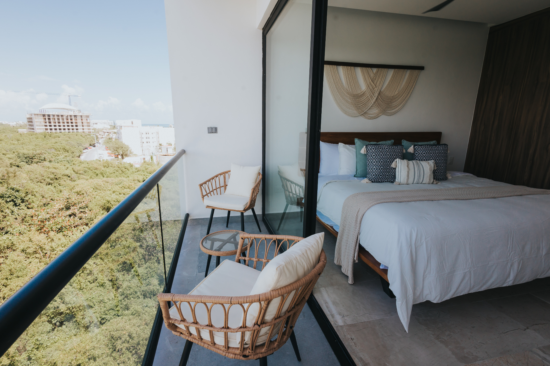 IX residence — bedroom opening to a rattan-furnished balcony with mangrove and ocean views